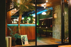 Um interior moderno com uma mesa de recepção de madeira, divisória de vidro e uma palmeira.