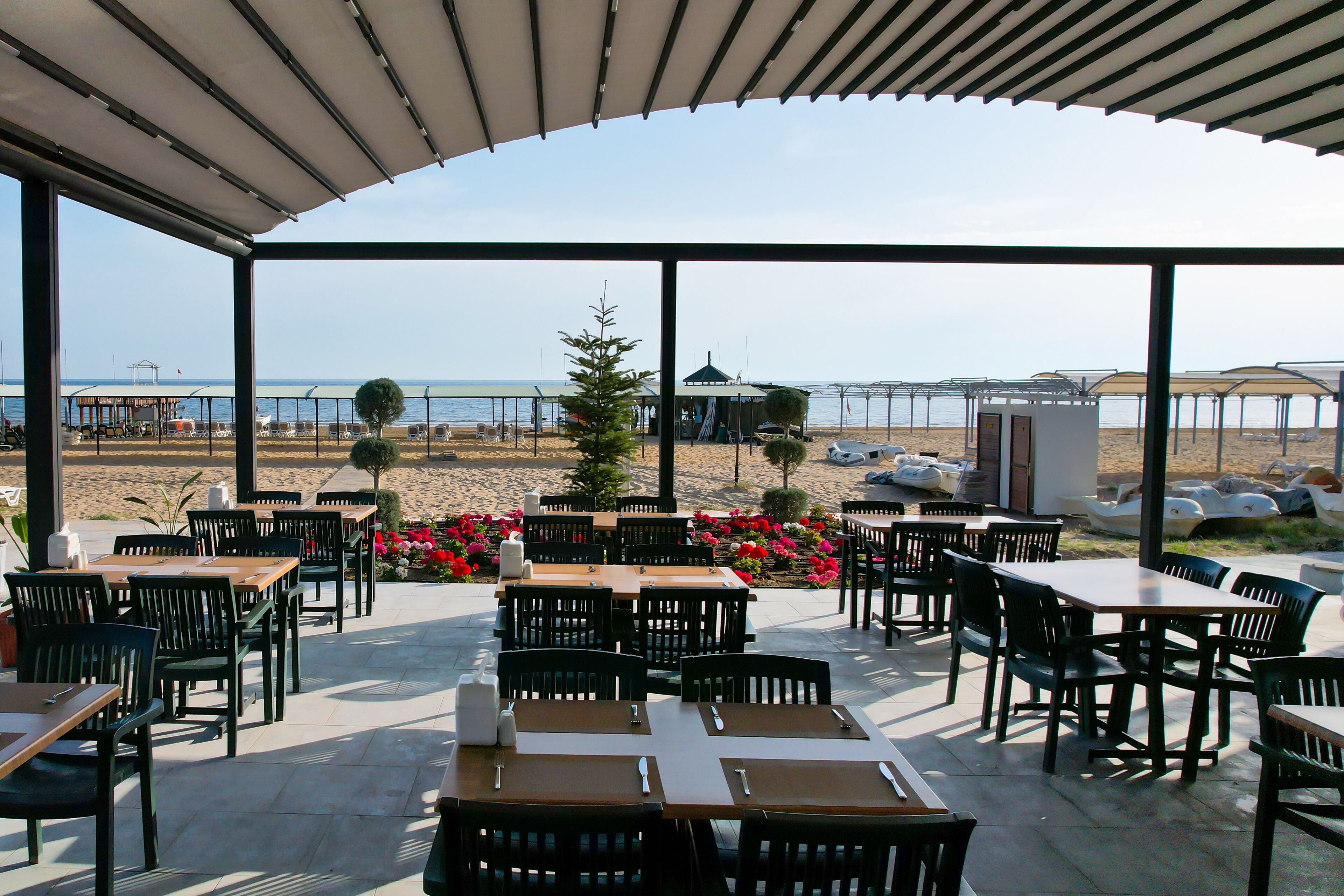 Un patio al aire libre con mesas y sillas, con vista a la playa.