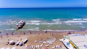 A beach with a pier, beach chairs, umbrellas, and a water sport area. - Side Village Hotel - All Inclusive (Manavgat)