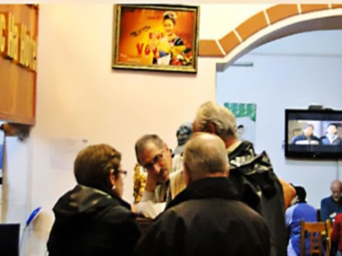 A group of people in a room with a television screen displaying a news program.