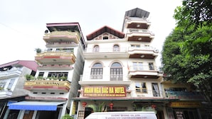 A multi-story hotel with balconies, a signboard, and a vehicle in front.