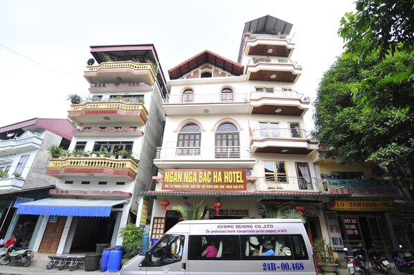 A multi-story hotel with balconies, a signboard, and a vehicle in front. - Ngan Nga Bac Ha Hotel (Bac Ha)