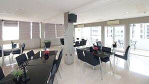 A modern conference room with glass tables, black chairs, and potted plants.