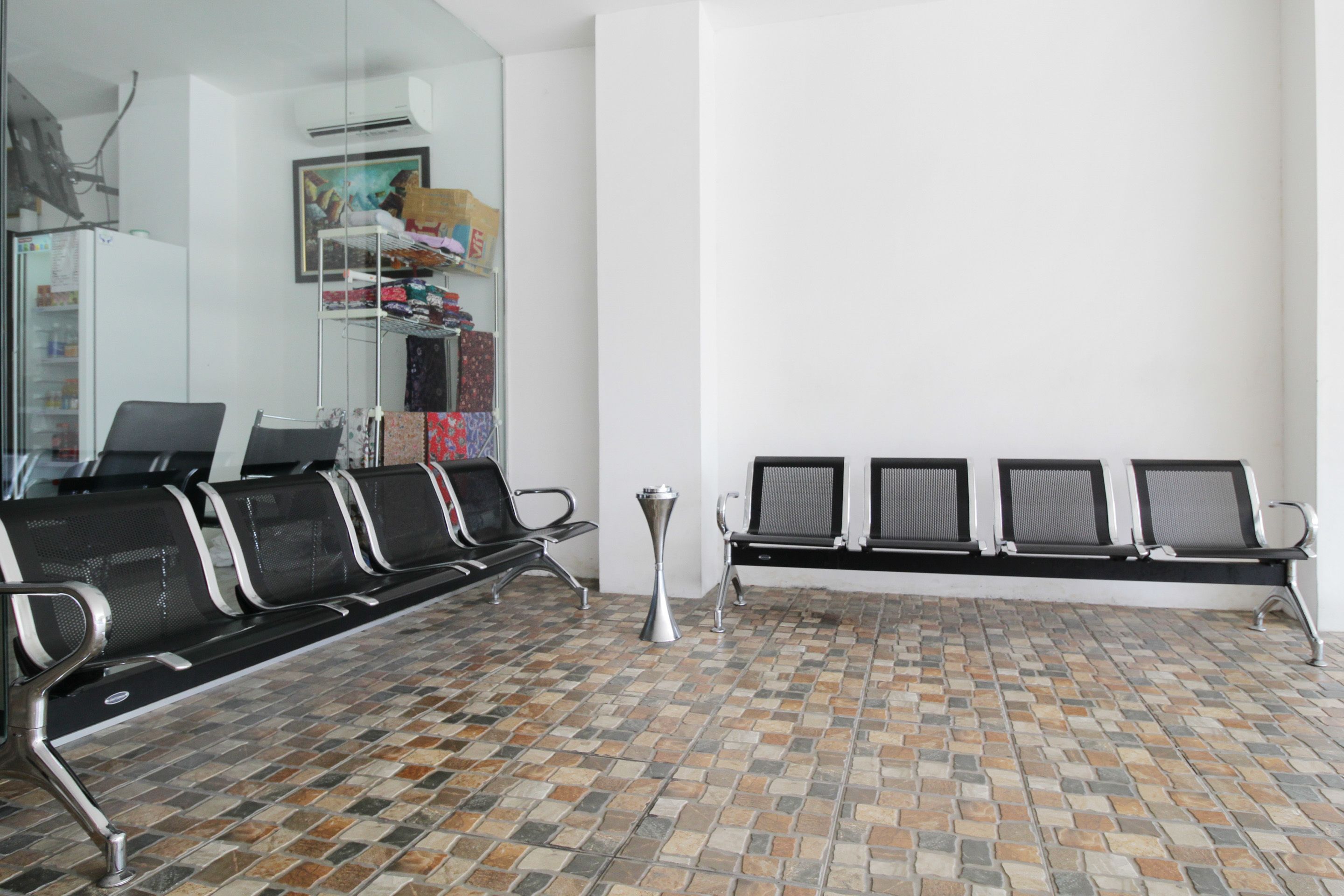 A waiting area with a tiled floor, a reception desk, and a bench with chairs.