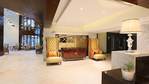Un hall d’entrée spacieux avec un sol en marbre, un comptoir d’accueil et un espace détente doté de fauteuils confortables.