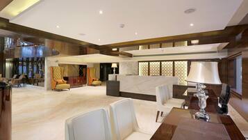 A spacious lobby with a reception desk, seating area, and a staircase leading to an upper level.
