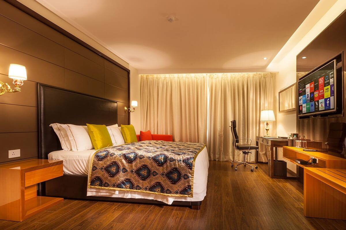 Een moderne hotelkamer met een groot bed, nachtkastjes, een bureau en een televisie.