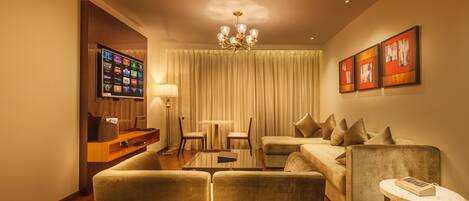 A modern living room with a sofa, armchairs, a coffee table, and a TV mounted on a wooden panel.