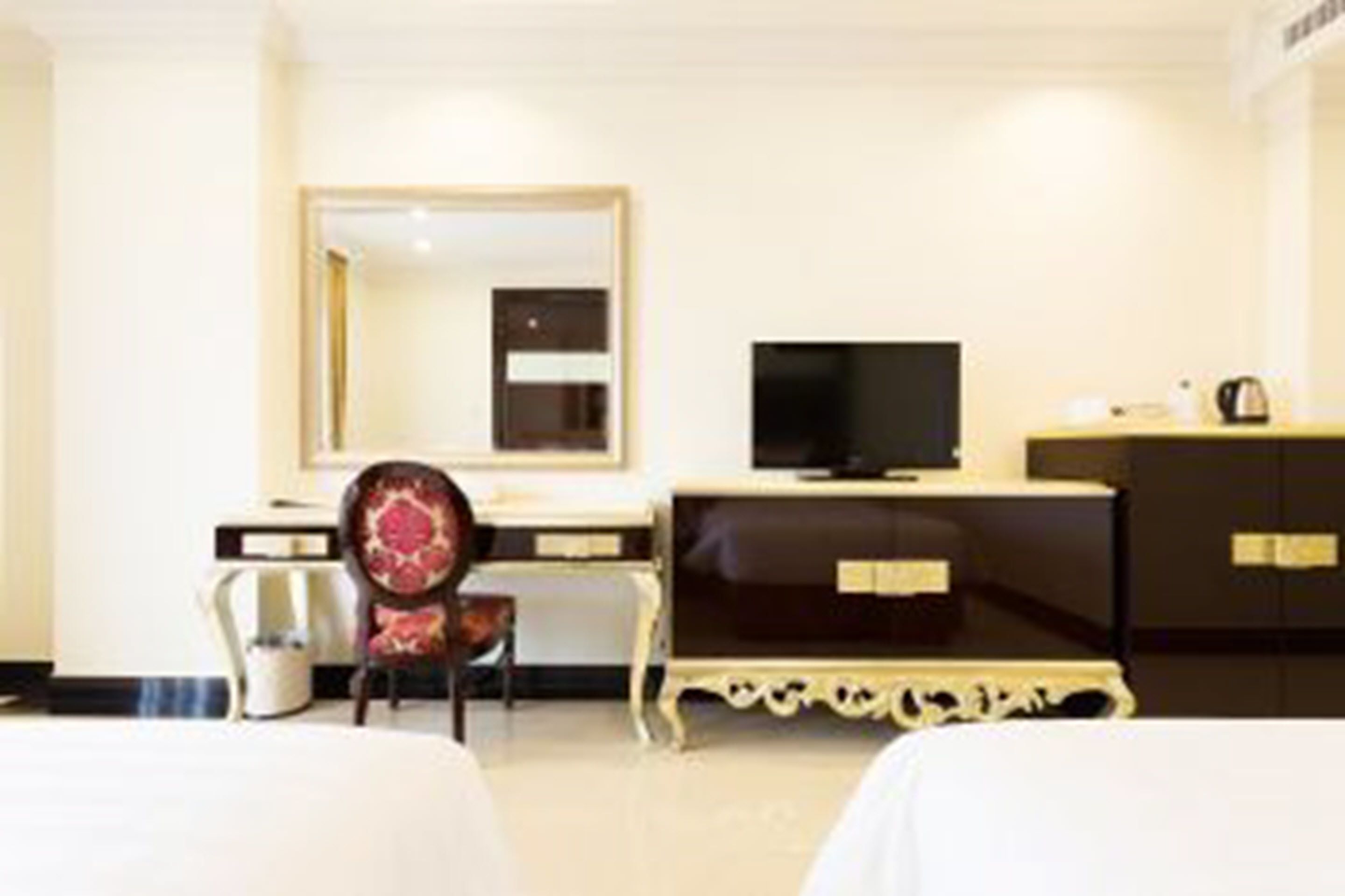 A hotel room with a bed, a desk, a chair, a television, and a wardrobe.