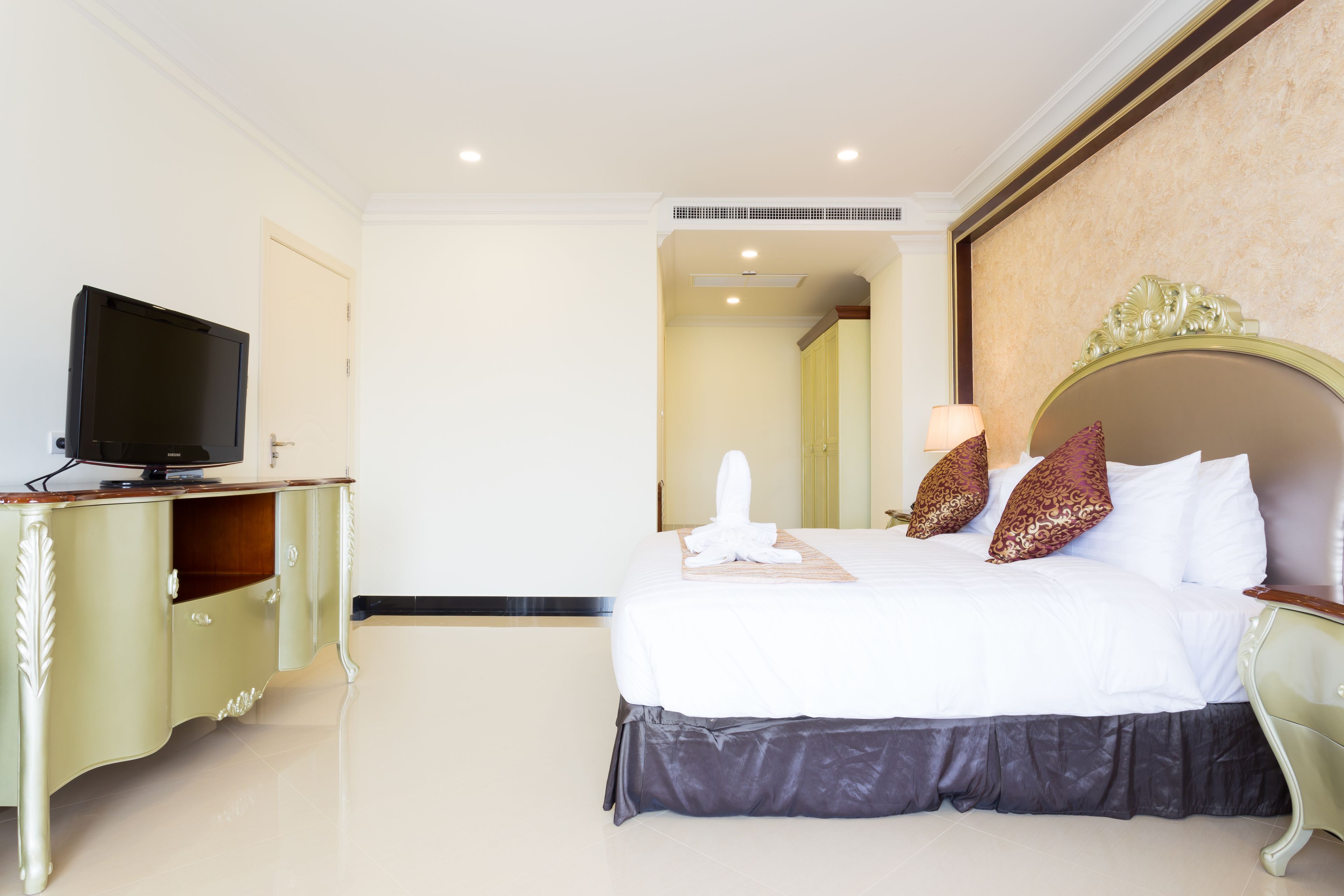 Une chambre d’hôtel avec un lit, un téléviseur posé sur une commode et un miroir au mur.