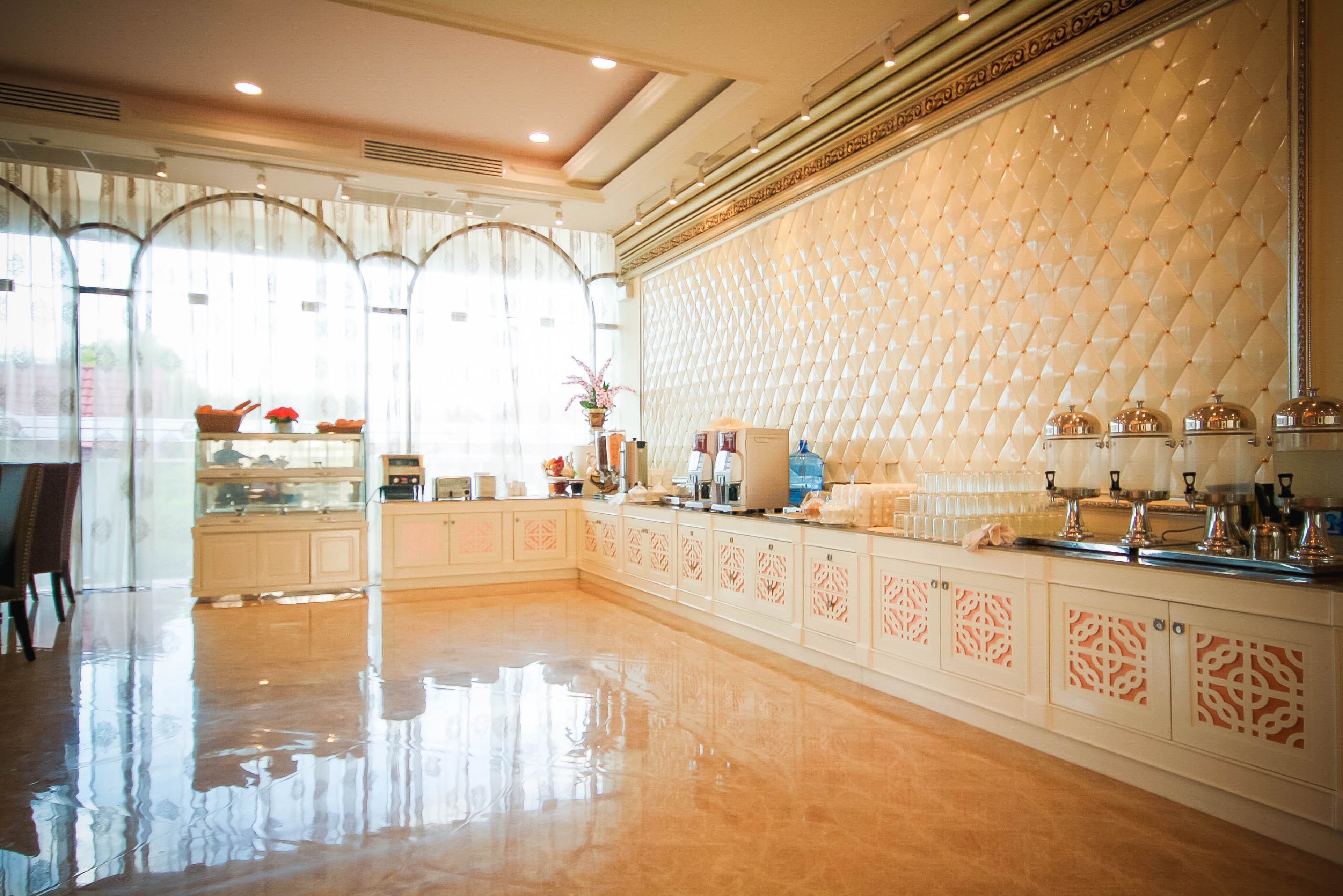 A spacious hotel lobby with a polished floor, a large seating area, and a decorative wall with a diamond pattern.
