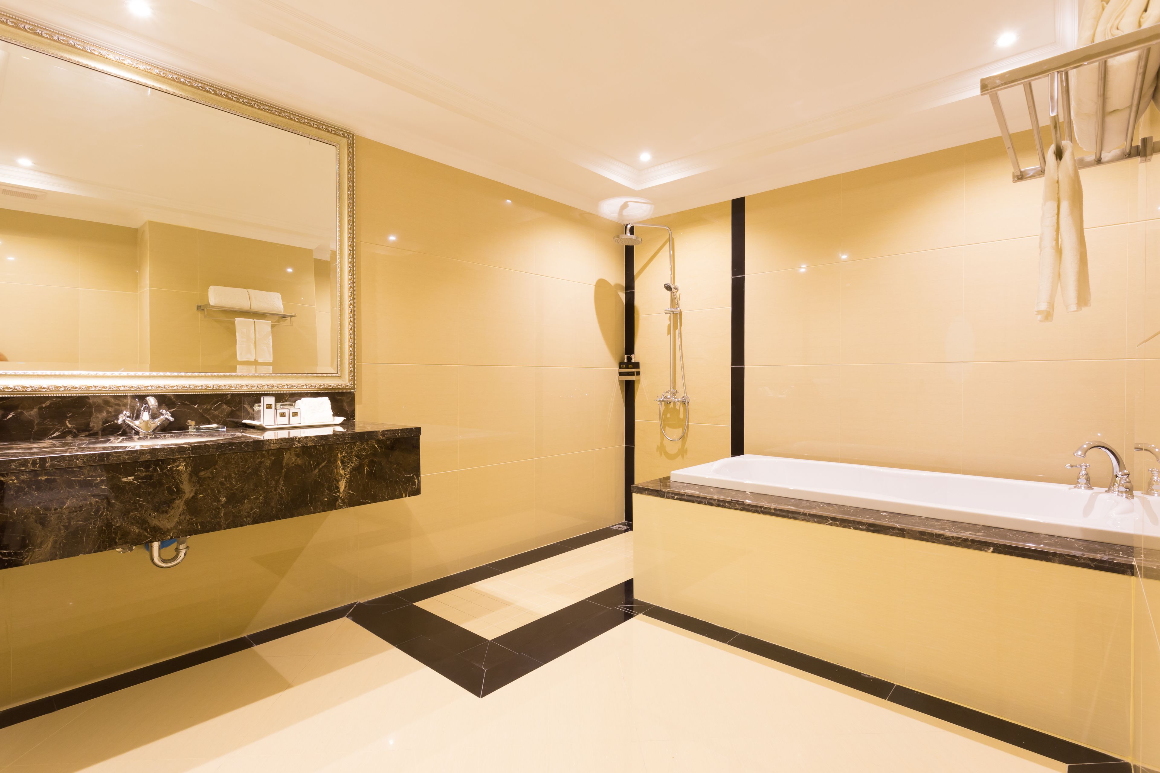A modern bathroom with a large mirror, a bathtub, and a shower.