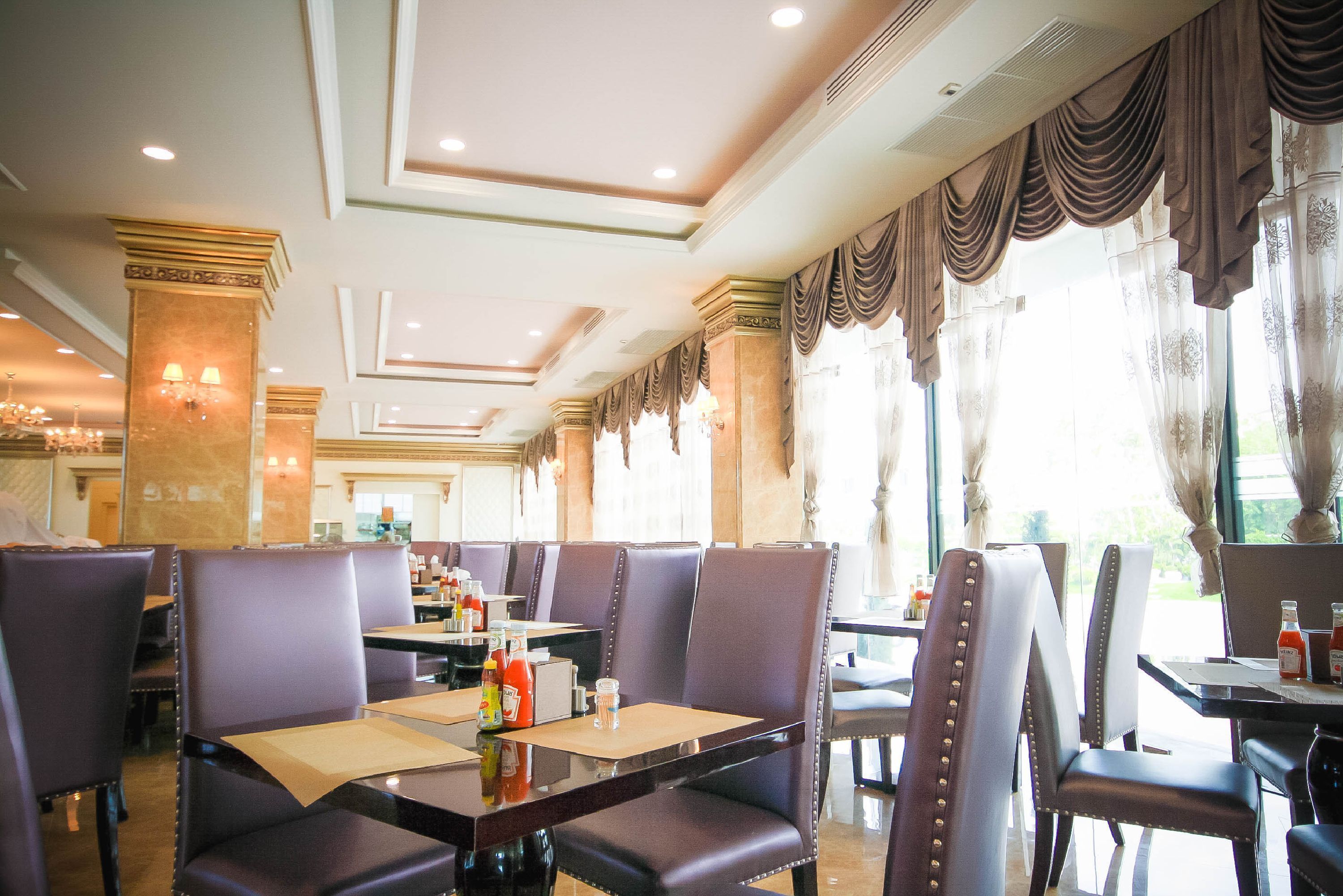 A restaurant with high-backed chairs, tables with menus, and a chandelier.