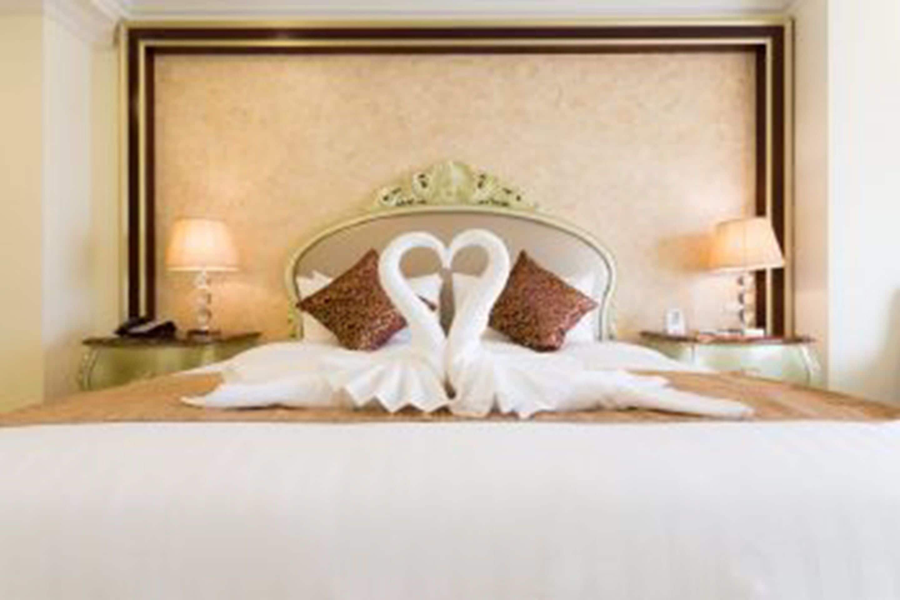 Habitación de hotel con una cama y una decoración de almohadas con forma de cisne.