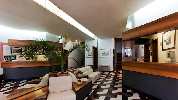A modern reception area with a reception desk, seating area, and a patterned floor. - Letizia Hotel (Orte)