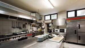 A commercial kitchen with stainless steel appliances, including a large stove, microwave, and refrigerator. - Letizia Hotel (Orte)