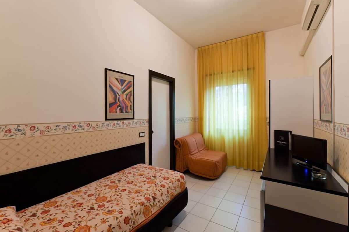 Une chambre d’hôtel équipée d’un lit, d’un bureau, d’une chaise et d’un téléviseur.