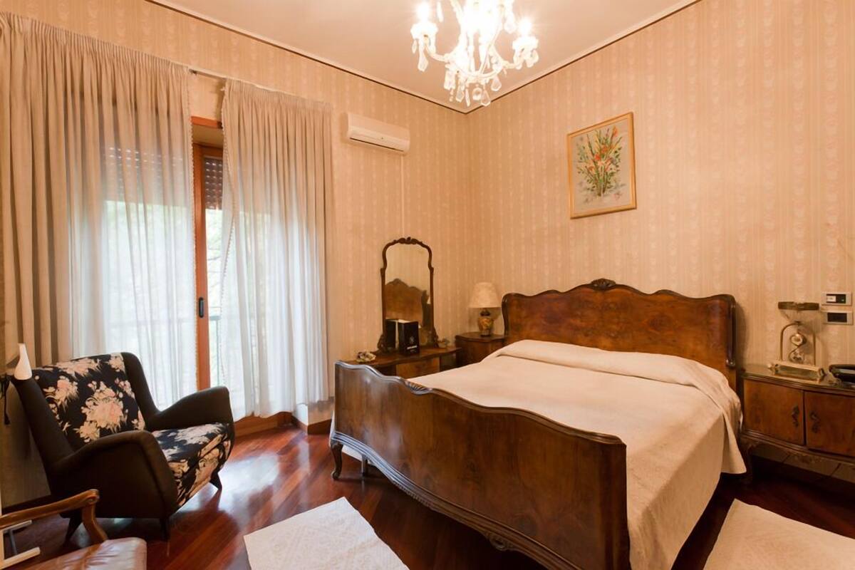 Une chambre à coucher avec un lit en bois, une chaise, une table de chevet et un lustre.