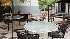 An outdoor patio with a round table and chairs, a large umbrella, and potted plants. - Letizia Hotel (Orte)