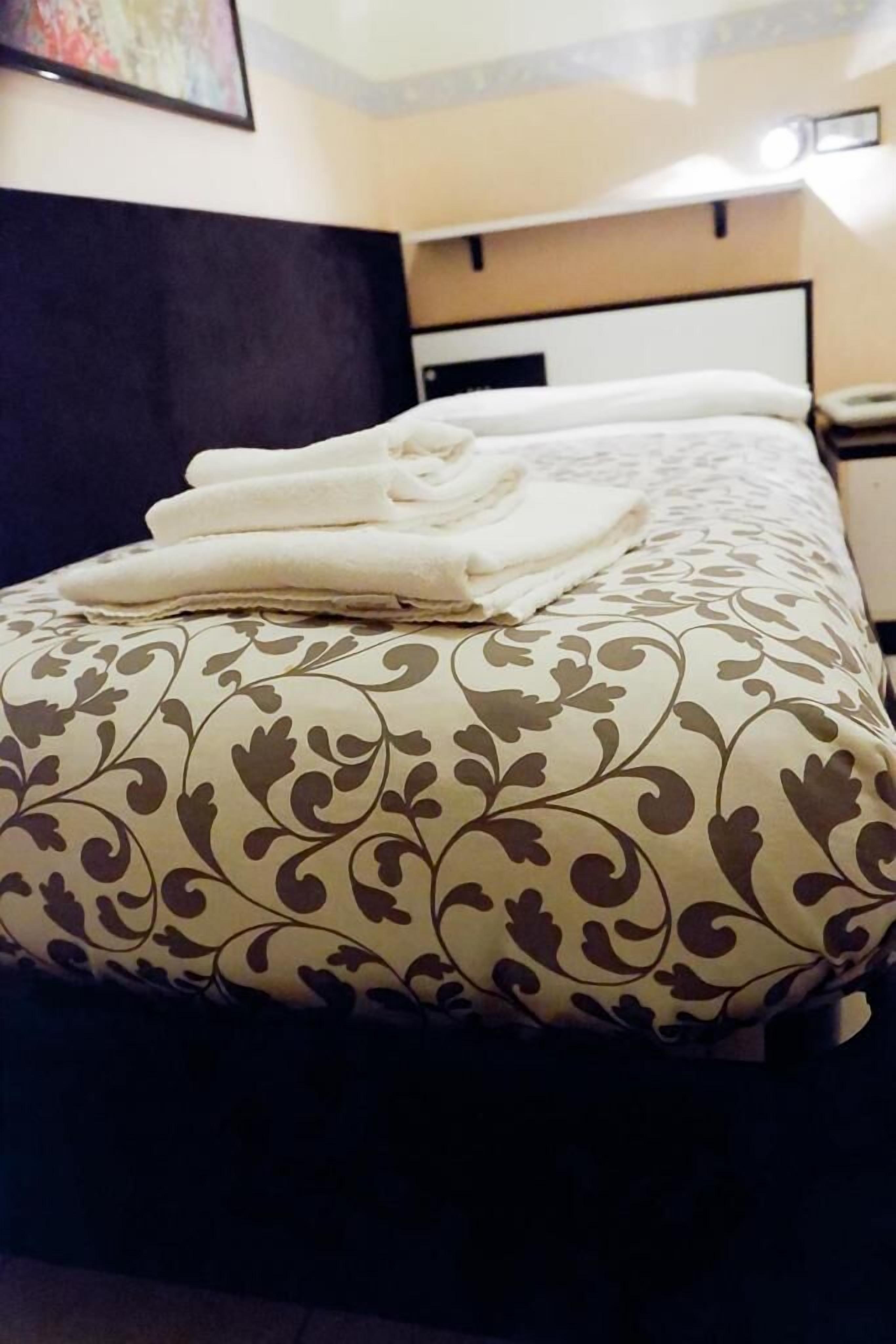 Un lit bien fait, avec une couvre-lit à motifs et des serviettes blanches pliées.