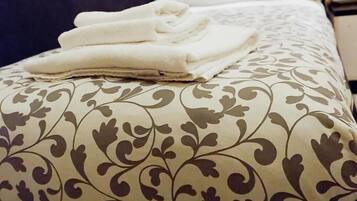 Un lit bien fait, avec une couvre-lit à motifs et des serviettes blanches pliées.