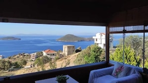 Una habitación con un ventanal que ofrece vistas al mar y a las colinas.