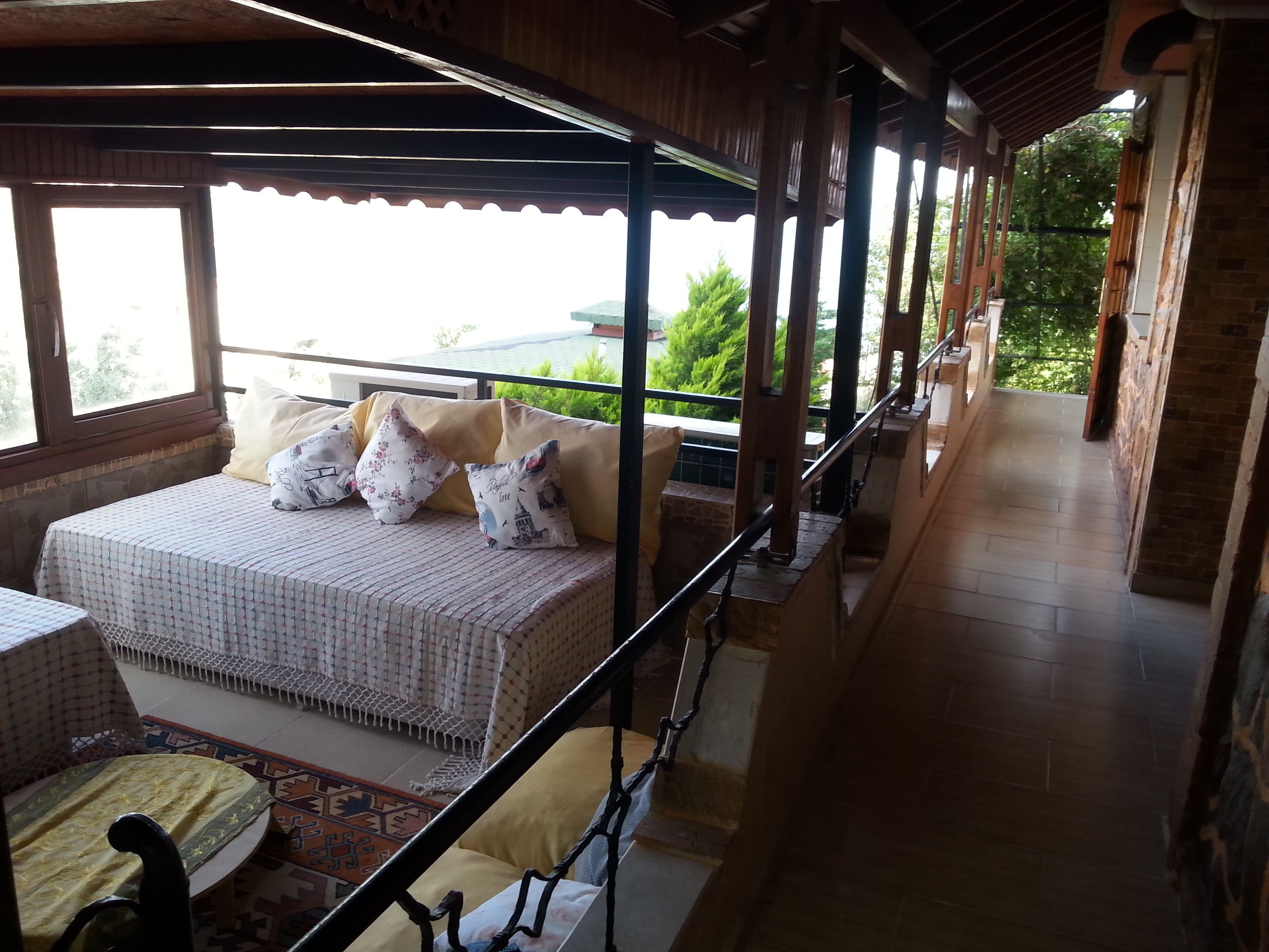 A balcony with a bed, a chair, and a railing.