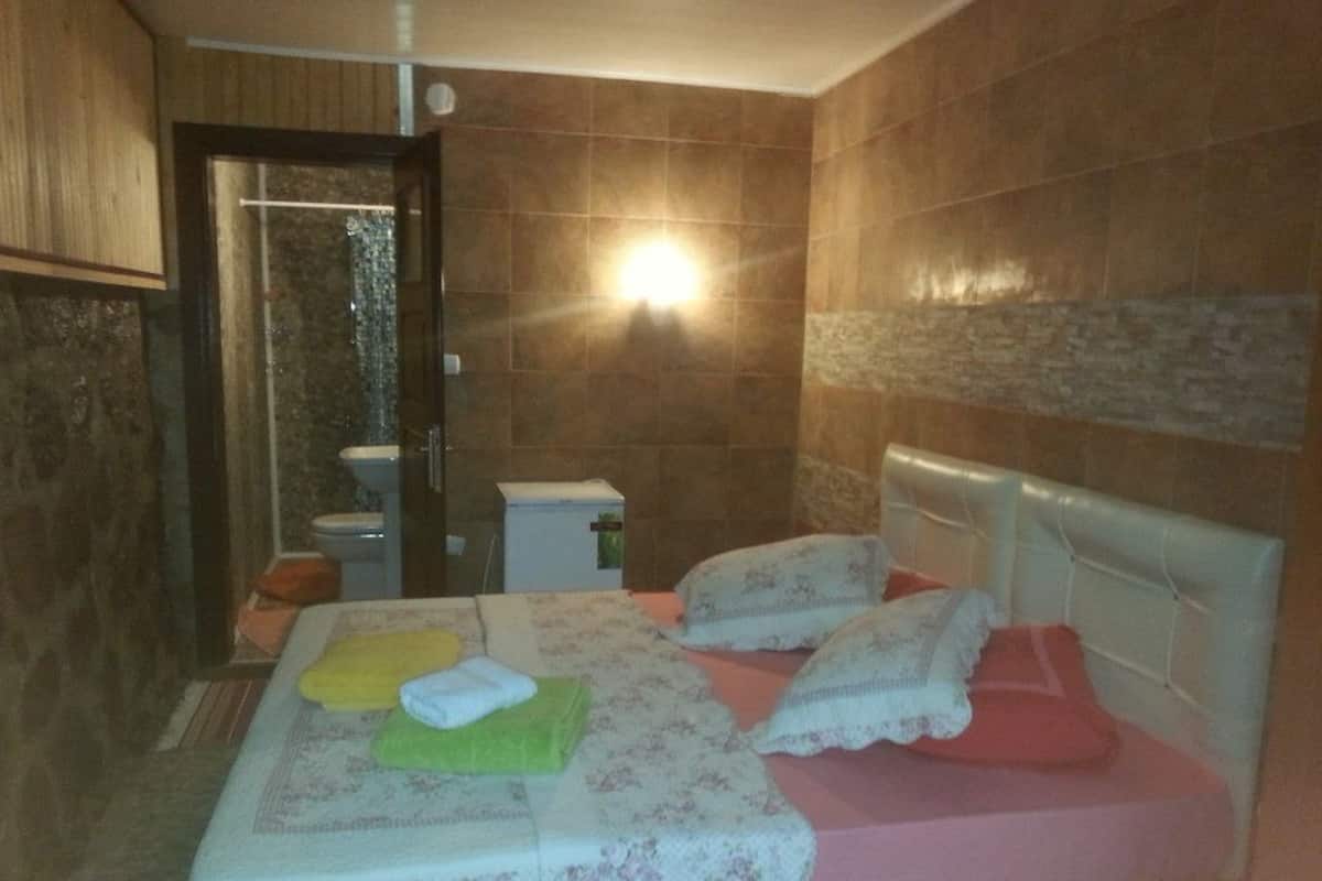 A hotel room with a bed, two pillows, a bedside table, and a nightstand.