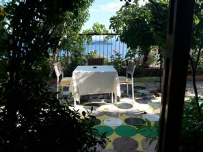 An outdoor seating area with a table and chairs, a patterned stone floor, and a view of the sea. - Tasev Butik Hotel (Dikili)