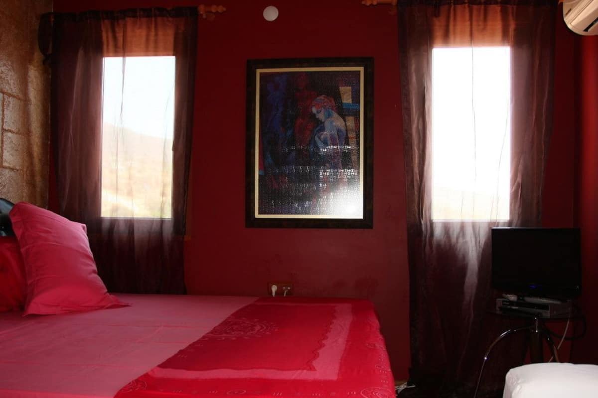 A room with a bed, a television, and a painting on the wall.