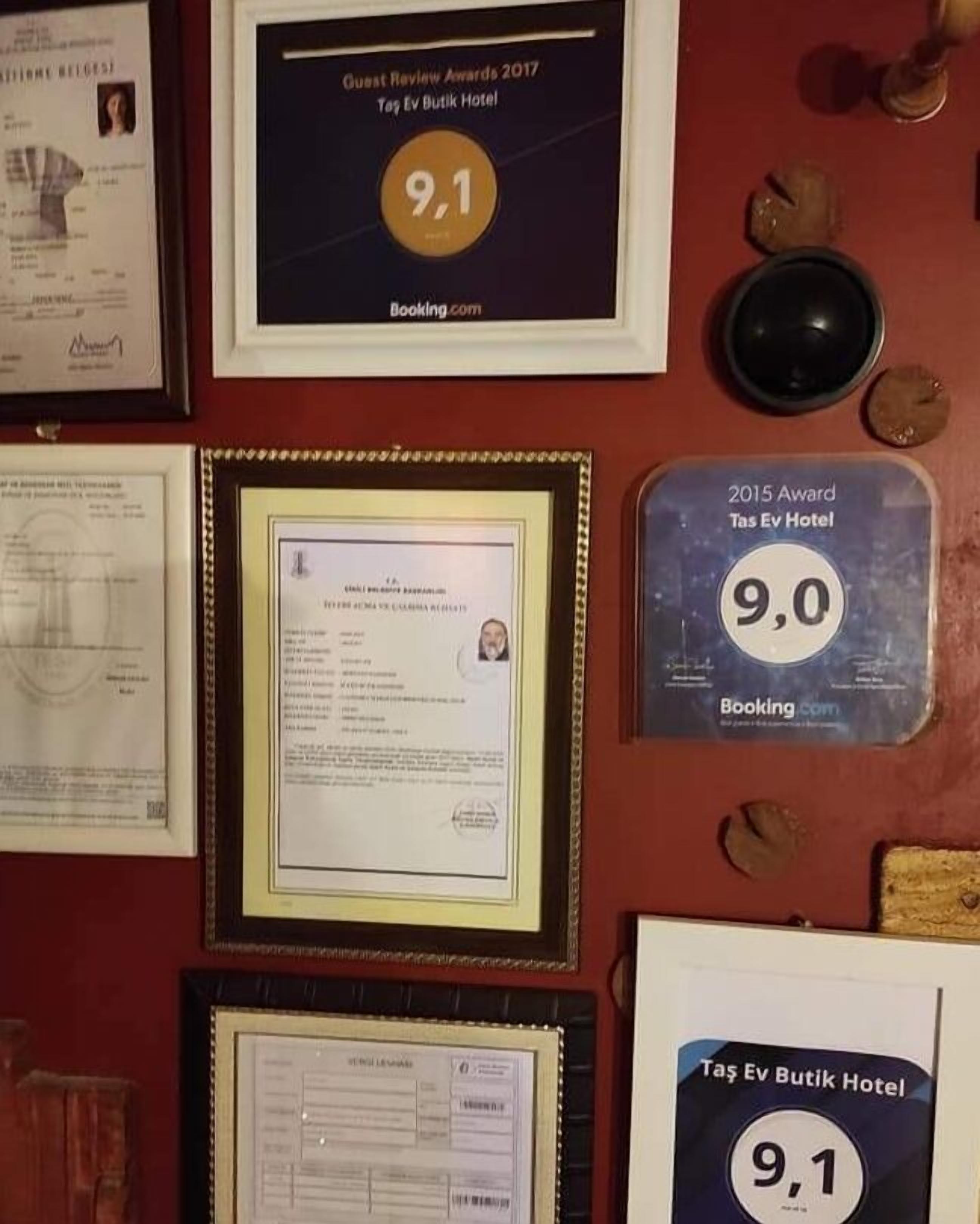 Framed awards and certificates on a wall, including a 9.1 rating from Guest Review Awards 2017 for Tas Ev Butik Hotel.