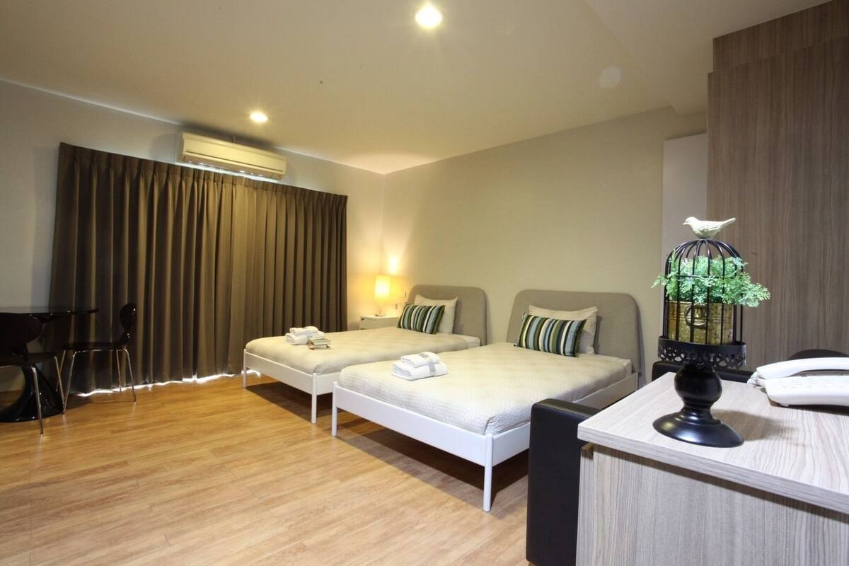 A hotel room with two beds, a desk, and a chair.