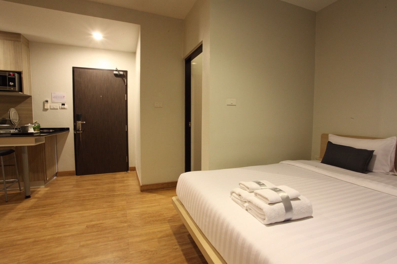 A hotel room with a bed, a desk, and a door.