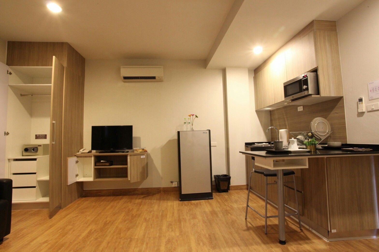 A compact kitchen with a microwave, refrigerator, and a small dining area with stools.