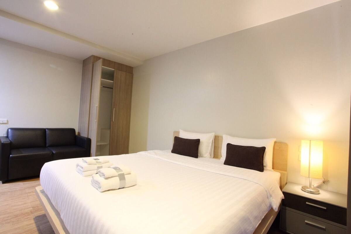 A hotel room with a bed, bedside table, lamp, and a wardrobe.