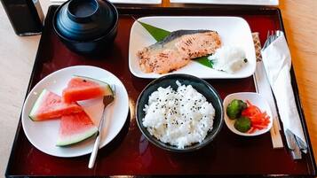 A tray with a salmon fillet, rice, watermelon slices, and a small dish of vegetables.