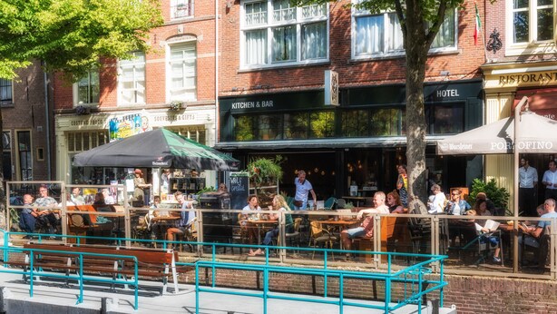 A riverside restaurant with outdoor seating, a bar, and a hotel across the street. - Wolf Hotel Kitchen & Bar (Alkmaar)