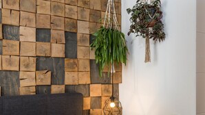 A wall with a wooden plank pattern, a hanging plant, and a geometric pendant light. - Wolf Hotel Kitchen & Bar (Alkmaar)