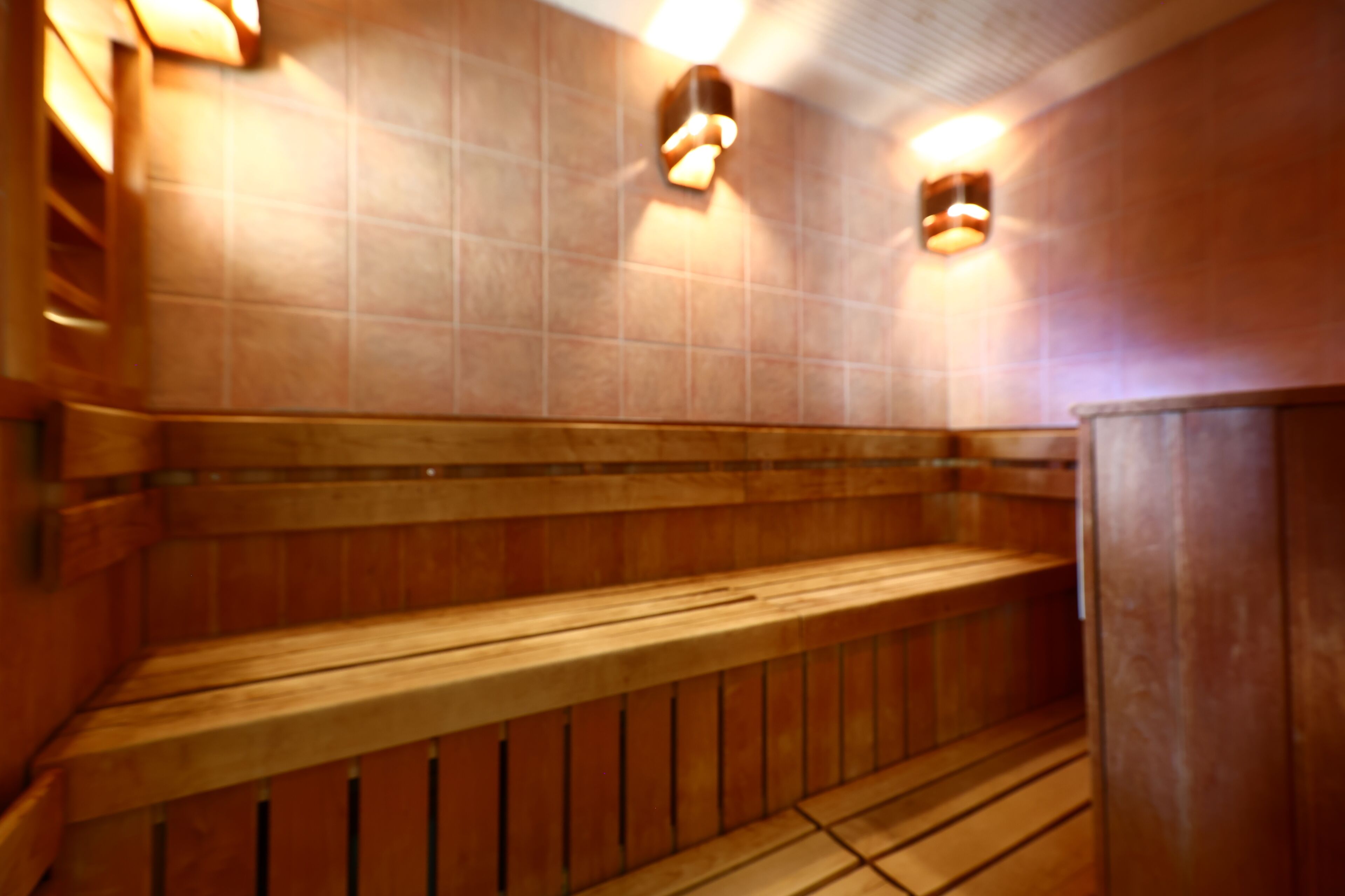 Uma sauna com bancos de madeira e iluminação na parede.