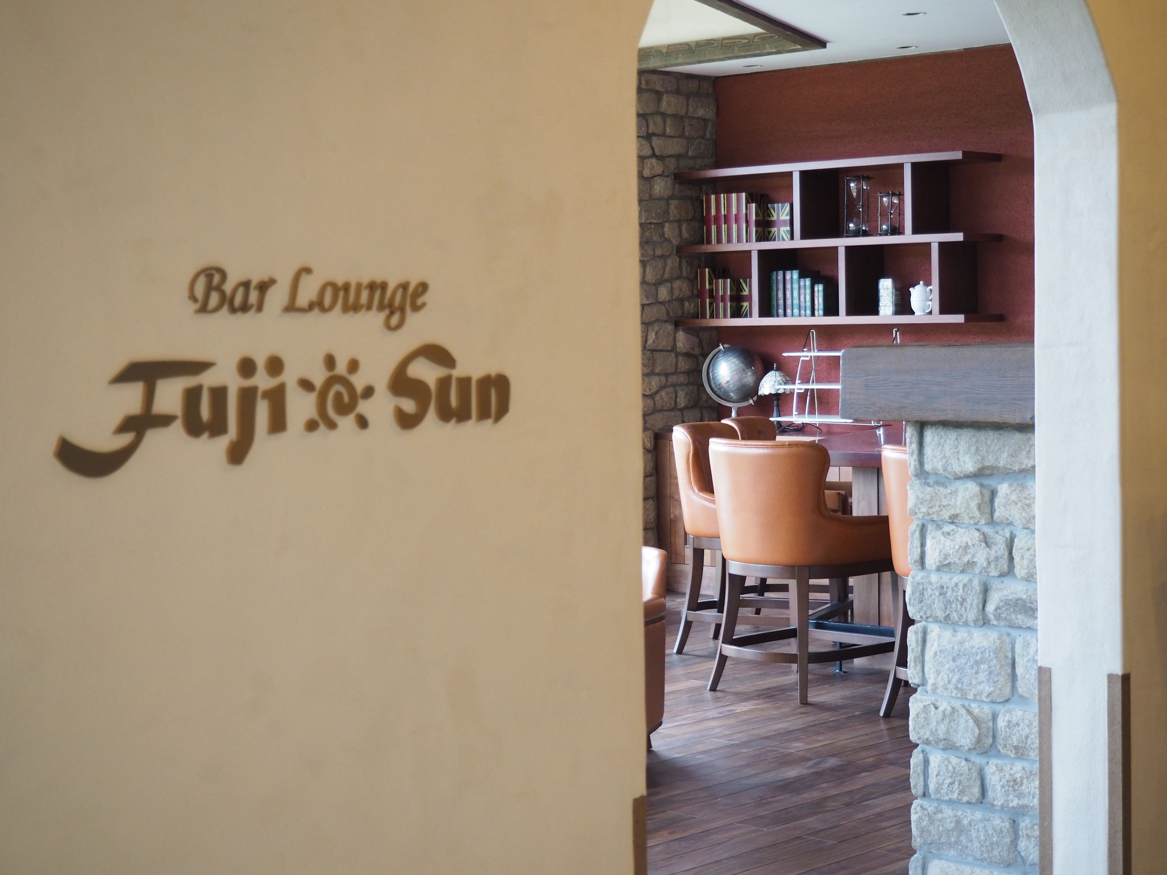 A bar lounge area with a stone wall, bookshelves, and leather chairs.