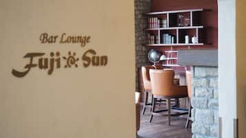 A bar lounge area with a stone wall, bookshelves, and leather chairs.