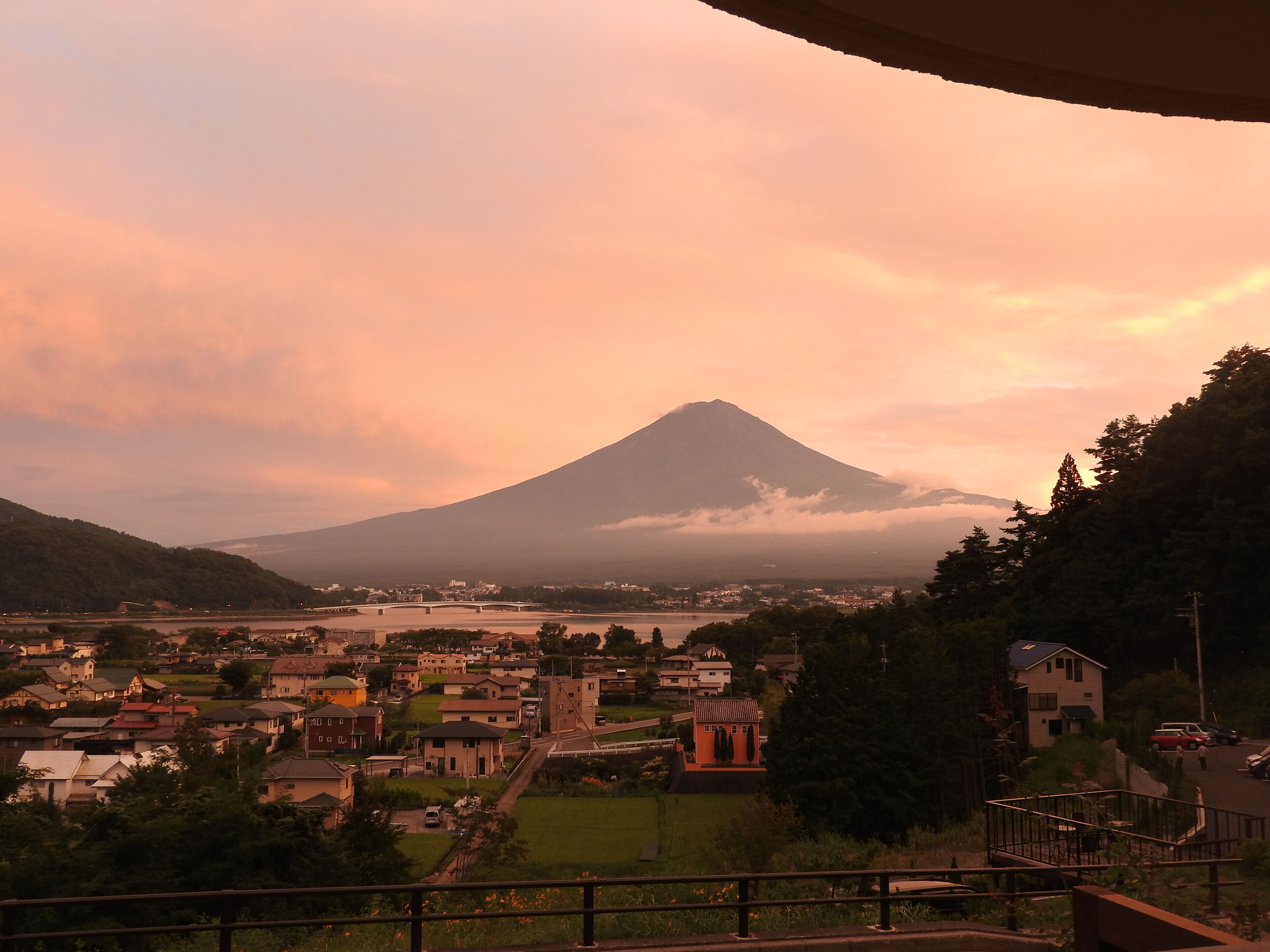 A town with a prominent mountain in the background, a bridge, and a river.