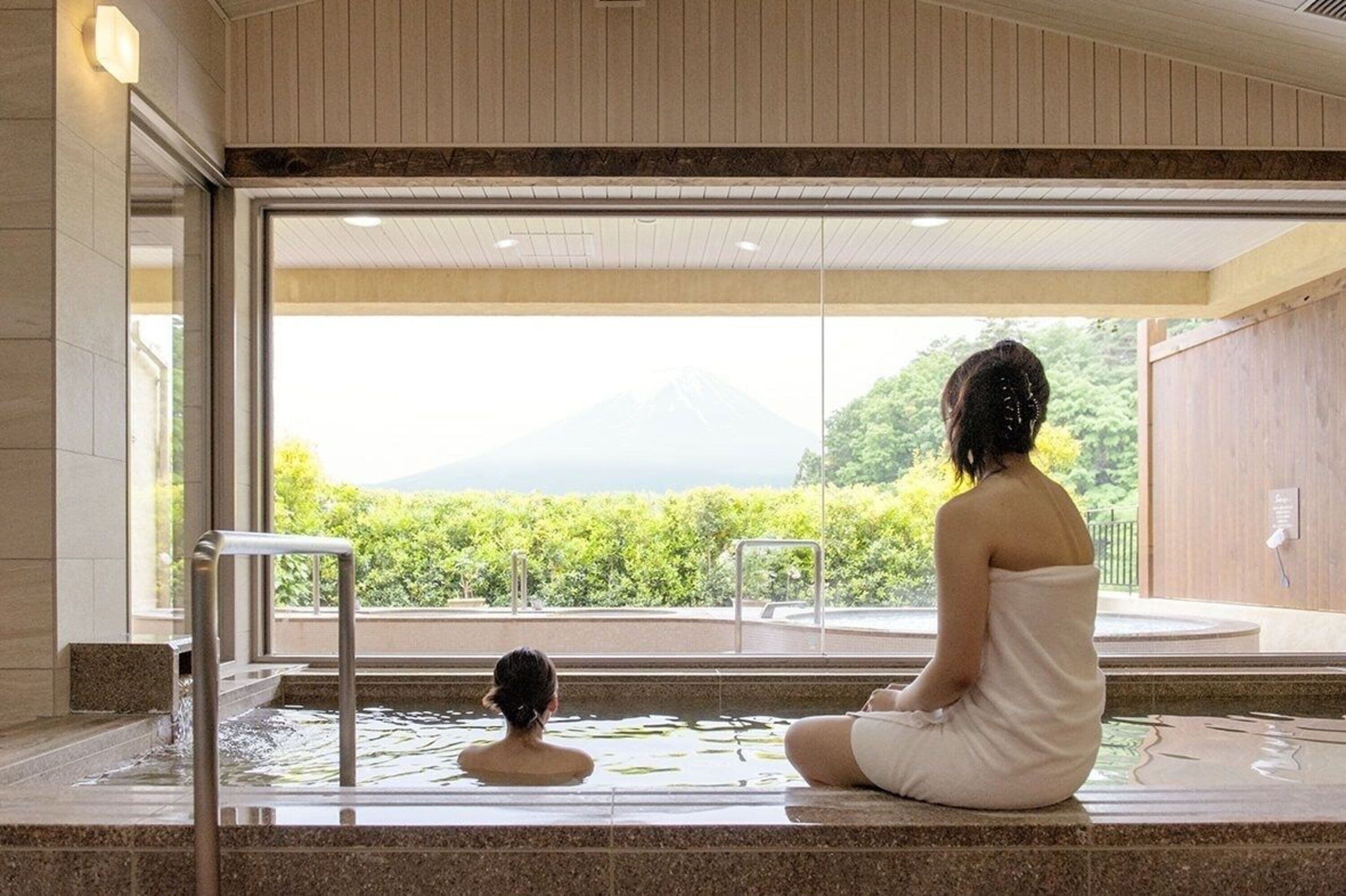 Une personne assise dans un bain à remous, avec vue sur la verdure et les montagnes.