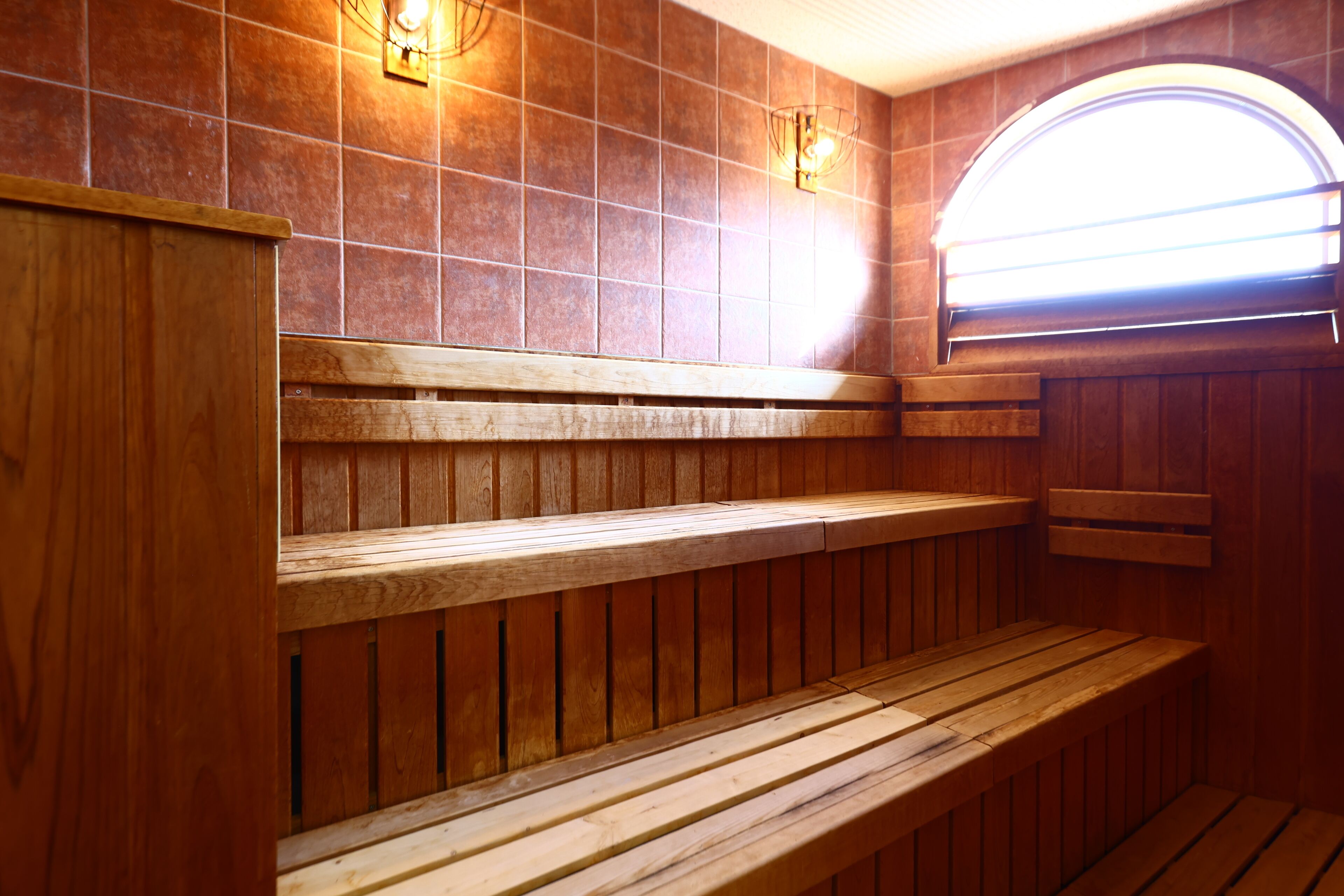 Una sauna de fusta amb bancs i una paret amb rajoles.