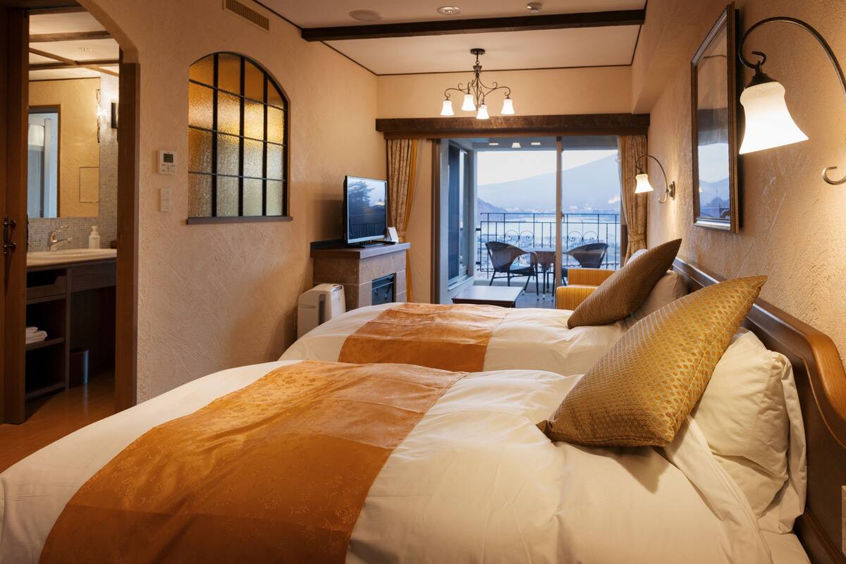 Une chambre d’hôtel avec deux lits, une télévision, un bureau et un balcon avec vue.