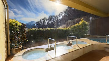 Relax in a serene hot tub area surrounded by lush greenery and a majestic mountain peak.
