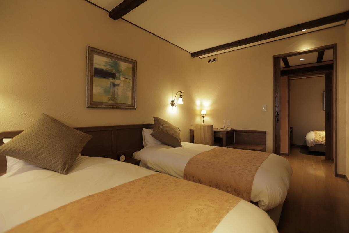 Une chambre d’hôtel avec deux lits, un tableau au mur et une lampe sur la table de chevet.