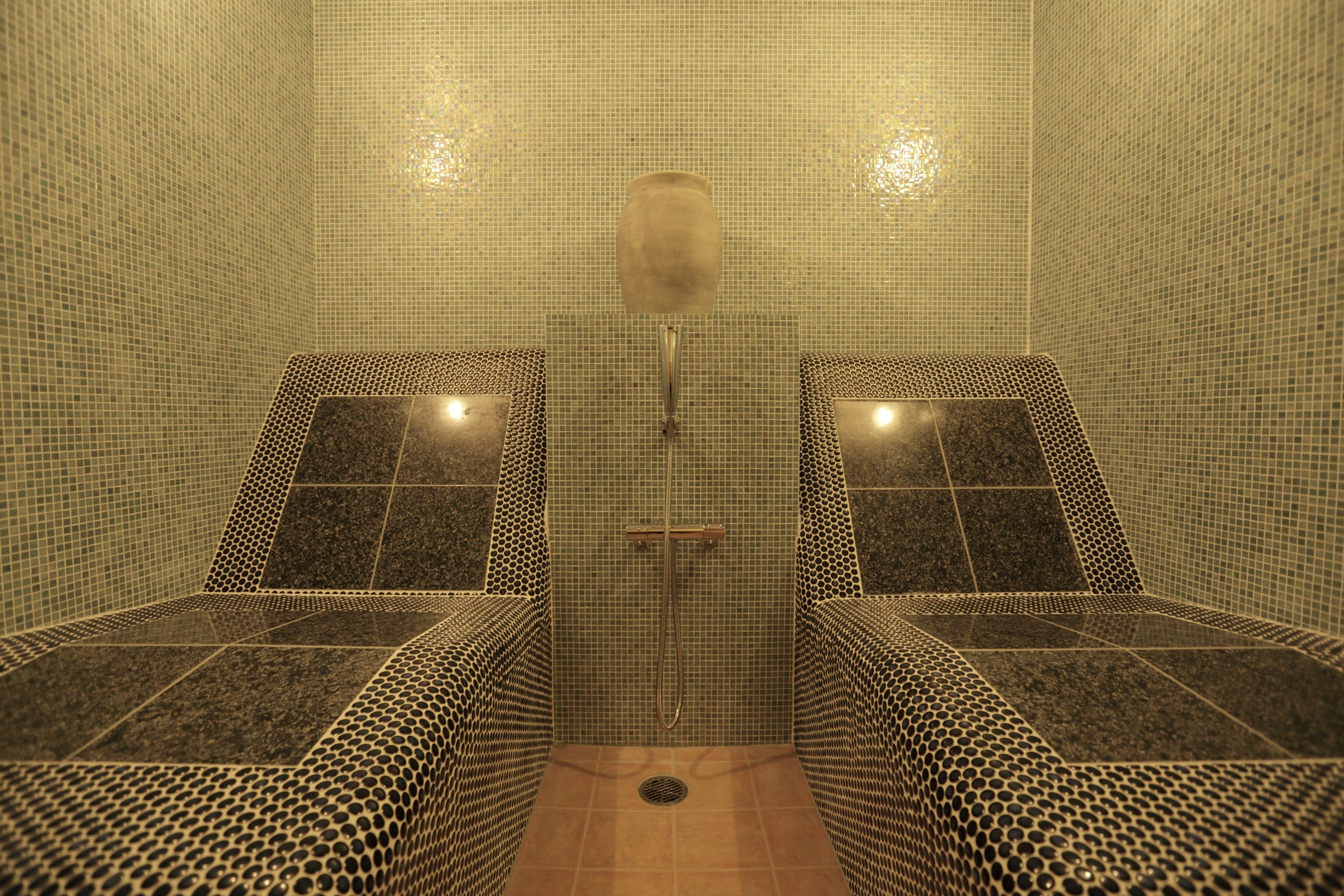 A spa room with two massage chairs, a tiled floor, and a shower area.