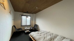 Un dormitorio pequeño y moderno con una cama individual, un escritorio con silla y una ventana con persianas.