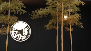 A logo with a stylized animal and waves, surrounded by tall bamboo plants.